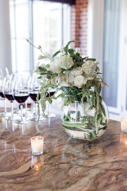 White floral centerpiece beside wine glasses and candles