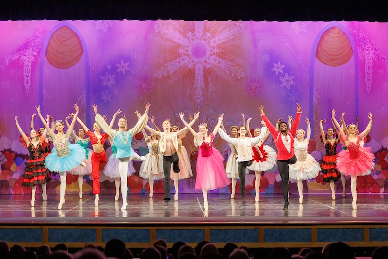 Ballet performers in colorful costumes take a bow onstage during a Nutcracker production.