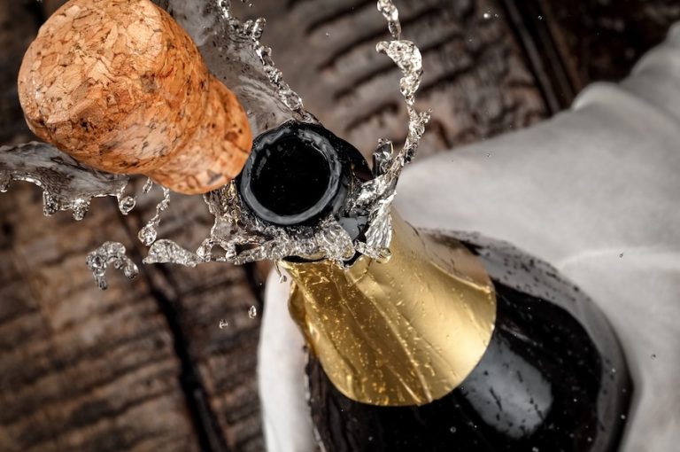 Champagne cork popping from a bottle as sparkling wine splashes outward.