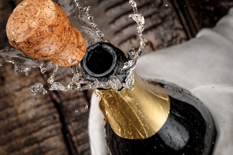 Champagne cork popping from a bottle as sparkling wine splashes outward.