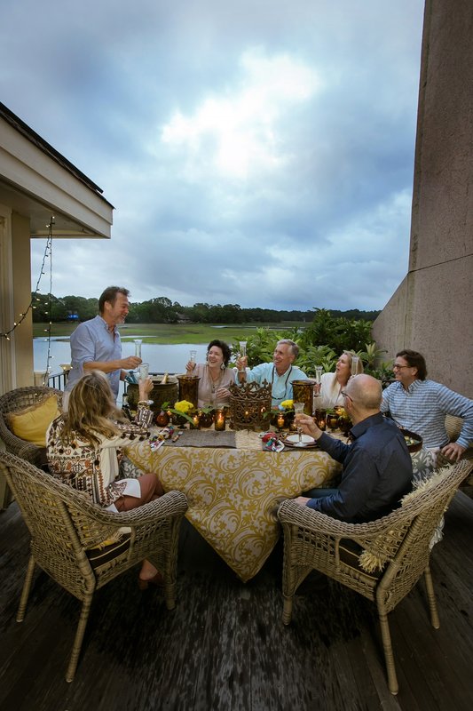 Guests raising glasses around an outdoor waterfront dining table
