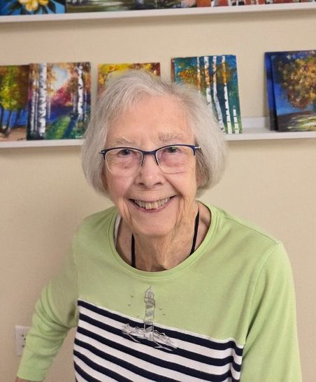 Portrait of Roma Holmes smiling and wearing glasses