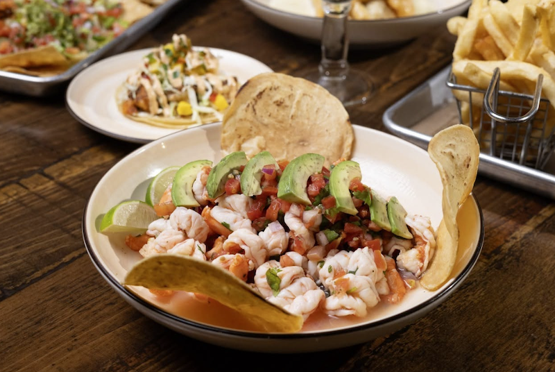 Shrimp ceviche served in a bowl with sliced vegetables and tortilla chips.