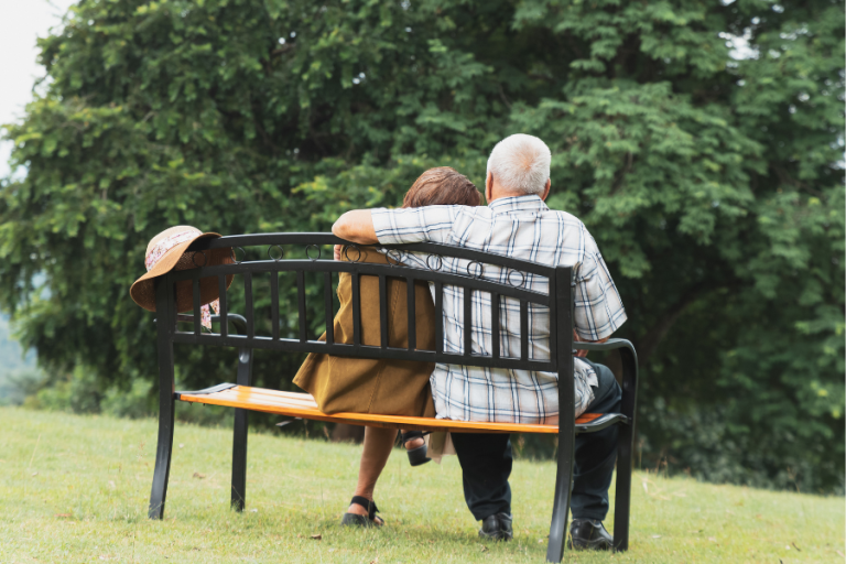Senior couple sitting on park bench overlooking water