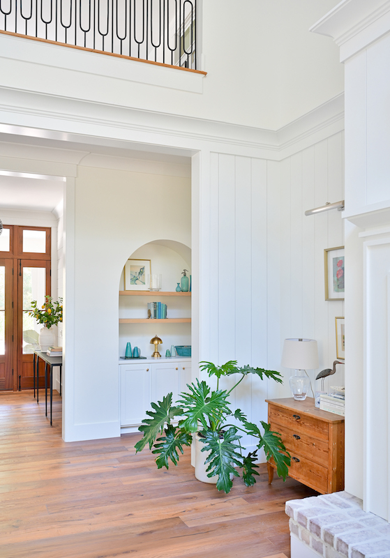 Spring Island interior with tall white walls, wood floors, built-in display shelves and an upper-level railing