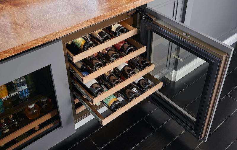 Open undercounter beverage cooler with wooden shelves holding wine bottles