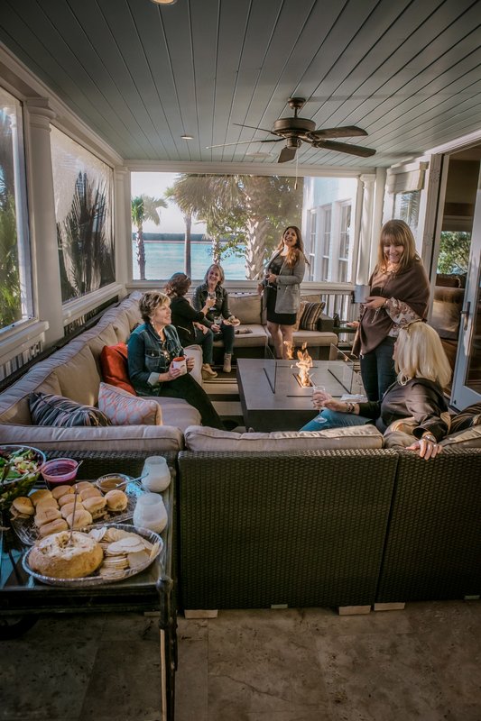 Guests gathered around a fire table on a covered porch
