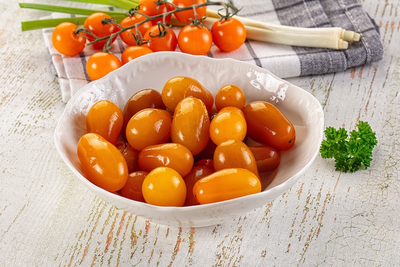 Red and orange cherry tomatoes arranged on a wooden serving surface.